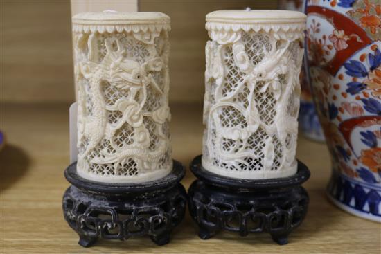 A pair of Chinese carved ivory tusk reticulated vases, carved with dragons among clouds and with carved and pierced hardwood stands